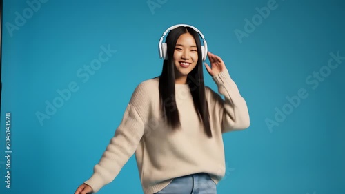 Young asian woman dancing and listening to music in headphones