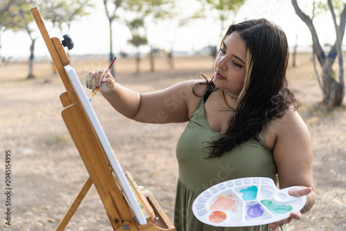 Young woman creating art on canvas in a park setting