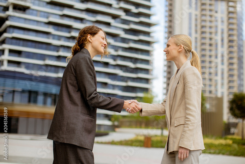 Two women shake hands in a ...