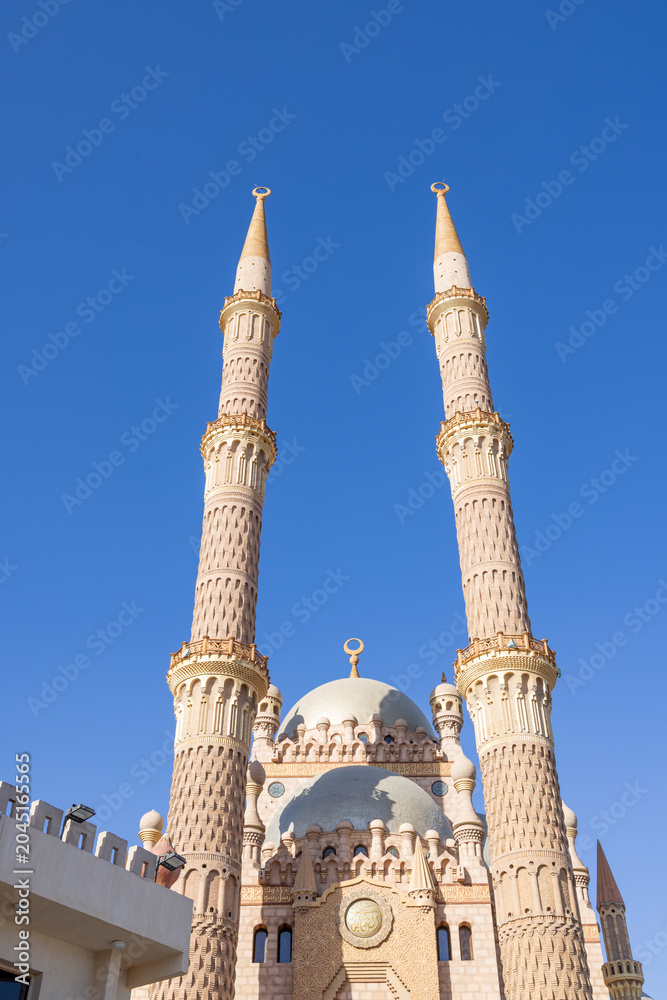 Obraz premium Al Sahaba Mosque in Sharm El Sheikh Egypt with twin minarets towering above the grand central dome showcasing magnificent Islamic architecture beneath a vivid blue sky in the summer time