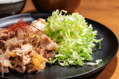 Photos 黒い皿に盛られた豚の生姜焼きと千切りキャベツのクローズアップ写真。レシピサイトやメニュー用