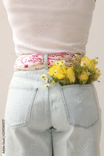 Woman with flowers in her pocket on light grey background, closeup