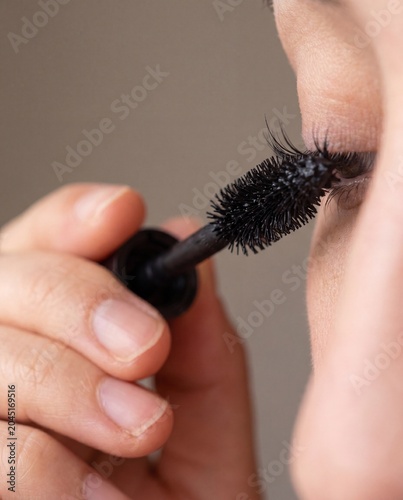 Hand applying mascara wand to single eyelash macro beauty close up routine