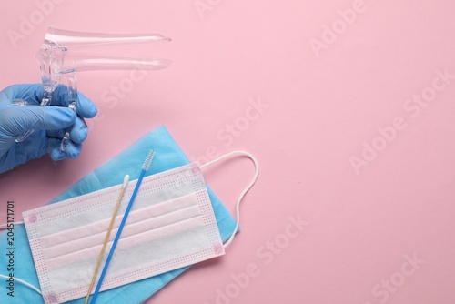 Foto Doctor with sterile gynecological examination kit and medical mask on pink background, top view