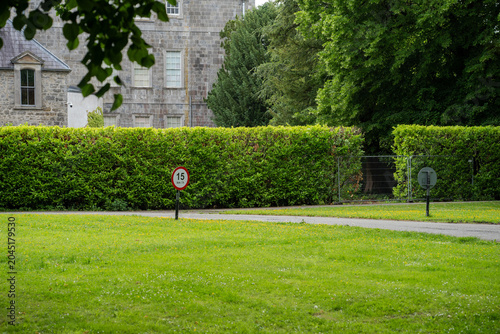 Foto Stone Manor House with Manicured Hedge and Speed Limit Sign