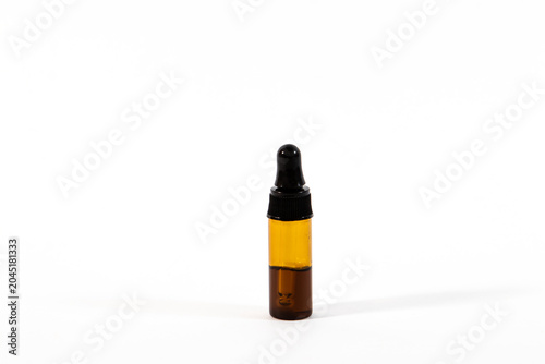 A small amber glass dropper bottle with a black screw cap and pipette isolated on a clean white background