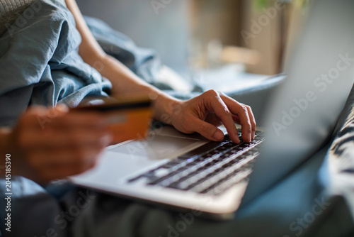 Hands paying online with credit card on laptop at home