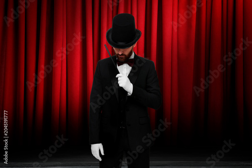 Fotografie Magician performing on stage with red curtains