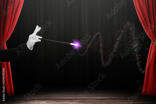 Canvas Print Magician performing trick on stage with red curtains, closeup