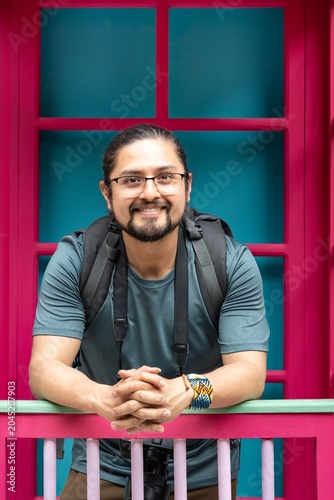 Smiling Male Photographer Leaning on a Colorful Balcony Railing