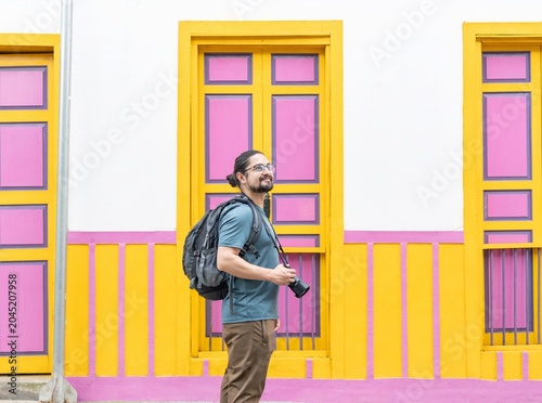 Male tourist with camera standing by colorful architecture
