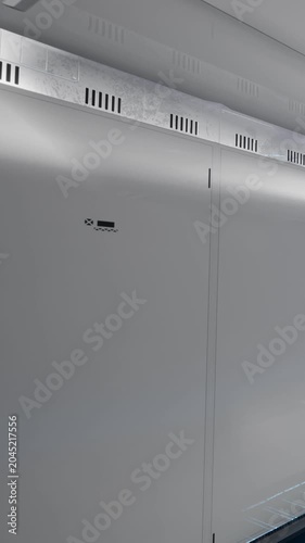 A wall is viewable in a room that has a high tech feel. The surface is smooth and features a lighted pathway along the ground. Equipment and tech details are visible.
