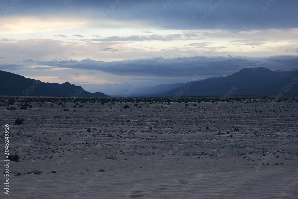 Fototapeta premium Moonrise Over Mountain Range in Desert at Dusk