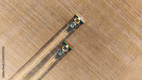 Bild auf Leinwand This aerial overhead shot captures two trains traveling along parallel railway tracks through a large, neatly cultivated farm field