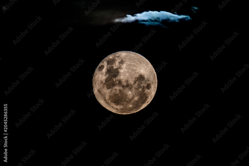 Fototapeta premium Waning Gibbous Moon Rising Amonst The Clouds