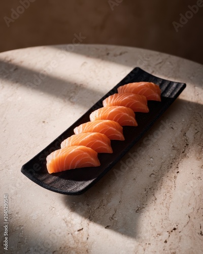 Elegant salmon sashimi arrangement on black plate with minimal garnish