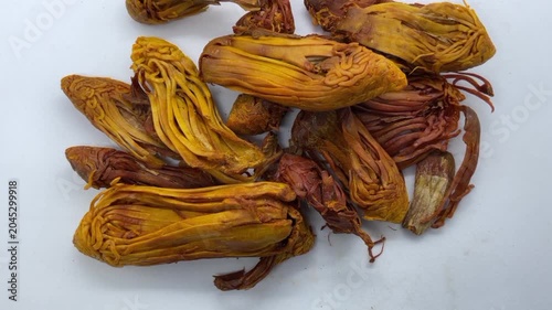 pile of dried Rampatri (Wild Mace) pieces isolated on a clean white background. The image showcases the intricate, reticulated, and lacy texture of these orange-brown whole spices. 