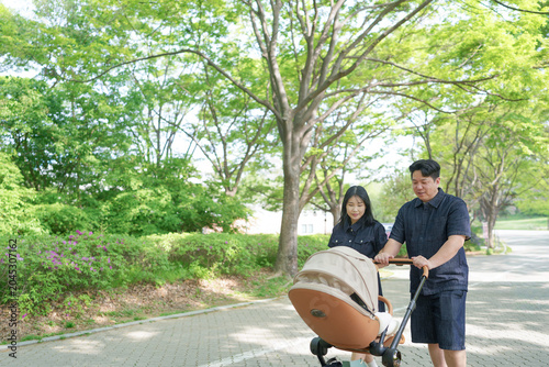 Slika na platnu Young couple walks park path with baby stroller