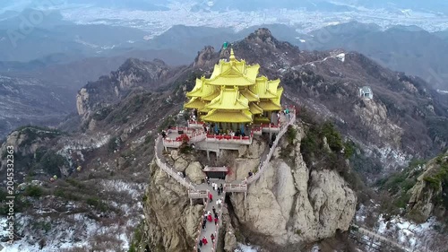 Aerial drone view of the famous golden summit Taoist temple complex perched on a rocky peak of Laojun Mountain in Luoyang Henan China. Golden roofs gleam above sea of clouds and jagged mountain ridges