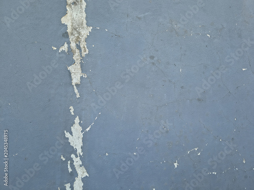 Blue painted concrete wall displaying peeling paint and weathered grunge texture