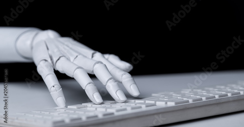 Robot hand typing on white computer keyboard close up view.