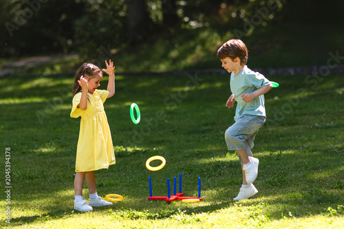 Two happy kids play throw a ring game when grilling outside on backyard in summer at garden party. Fun outdoor children games. Childhood and summer vacation. Copy space. High quality photo