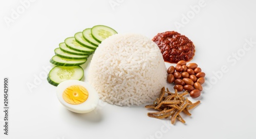 Authentic Nasi Lemak, a fragrant coconut rice dish from Malaysia, features sambal chili paste, fried anchovies, peanuts, boiled egg, and sliced cucumber, presented appealingly for culinary