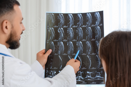 Male doctor showing MRI scan of spine to patient in clinic, closeup