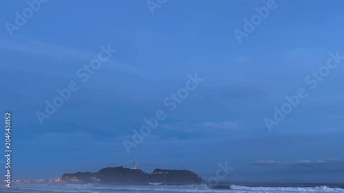 穏やかな夕暮れの海から望む江ノ島と柔らかな街の灯り