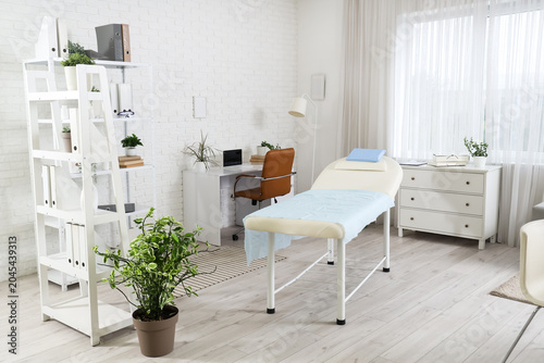 Interior of medical office with workplace, couch and shelf units
