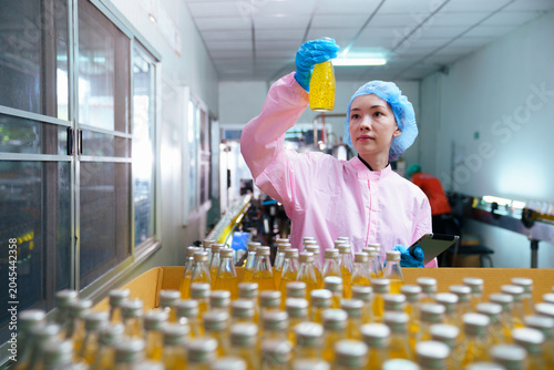 Quality control inspector monitoring juice production line in food factory