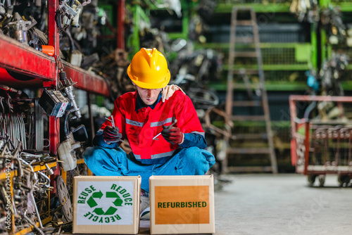 Male technician inspecting used auto parts for refurbishing and recycling in scrapyard