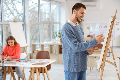 Male student painting on ca...