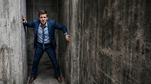 Businessman Facing Stress in Concrete Maze Corridor