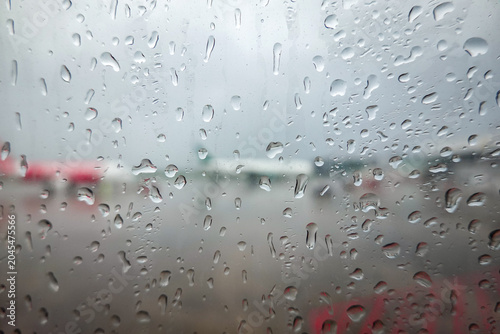 фотографія The image depicts an airplane window during a rainstorm, with raindrops clinging to the surface
