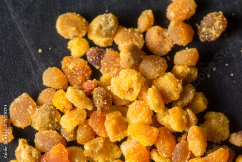 Close-up of scattered bee pollen granules on a dark surface.