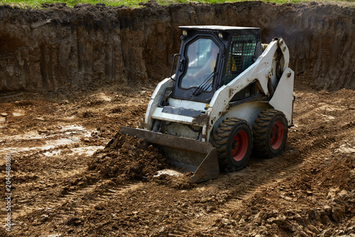 Heavy machinery moves dirt at a construction site with a clear focus on ground leveling and preparation for building