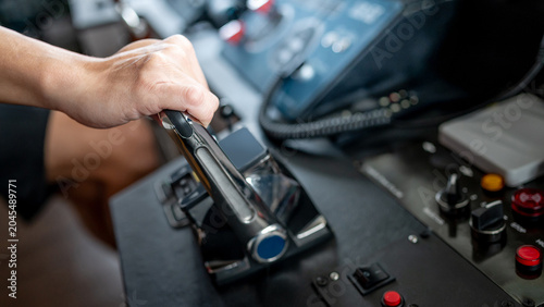 Foto Captain hand holding throttle control or engine control lever on modern boat dashboard in wheelhouse or ship bridge
