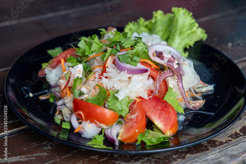 Thai spicy and sour glass noodle with seafood salad on black plate, called Yam Woon Sen Talay or Yum Wun Sen Talay. Close up