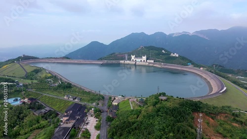 Aerial view of mountain reservoir and dam surrounded by green hills