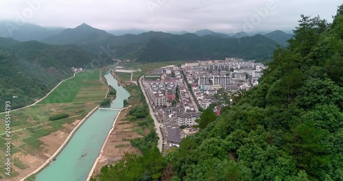 Aerial view of mountain town with river canal, farmland and forest