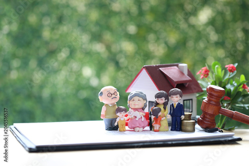 Family estate planning and legacy concept with multigenerational figures, house model, gavel, and coins on contract document, symbolic of legal property rights and inheritance management.
