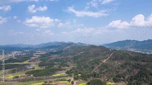 Aerial view of rural farmland and mountain landscape under blue sky