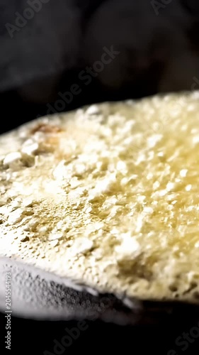 Yellow butter melting on a hot black frying pan.