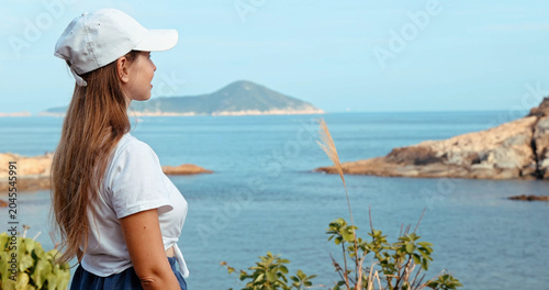 Fotografie Young woman in white cap admiring scenic ocean view