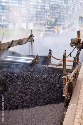 Принти на полотні Asphalt is being laid down on a city street as workers operate heavy machinery