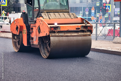 Φωτογραφία Asphalt is being laid down on a city road by a large roller machine