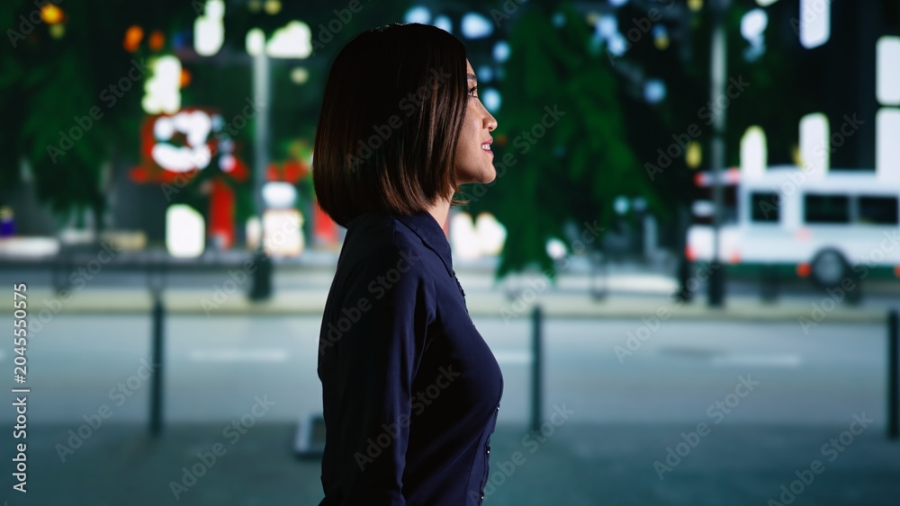 Fototapeta premium Asian person walking around town under streetlights, enjoying urban promenade near city center district. Young woman relaxing on stroll at nighttime, admiring downtown and skyscrapers. Handheld shot.