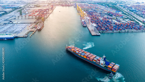 Foto cargo container ship maneuvering near a busy commercial port terminal loaded with freight boxes