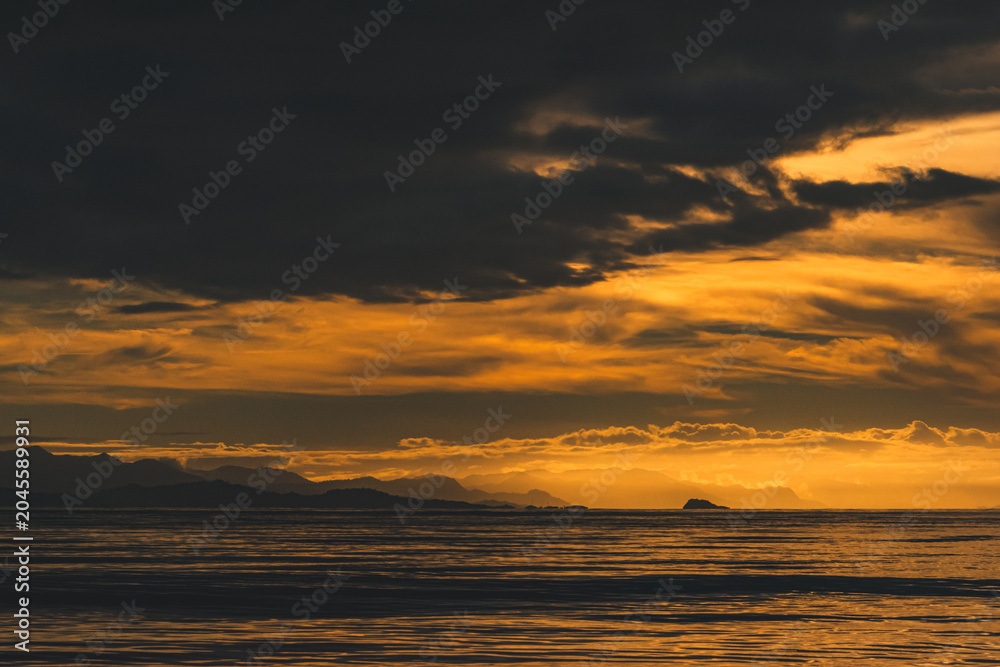 Fototapeta premium Dramatic Orange Twilight Sky Over Sea and Mountain Silhouettes